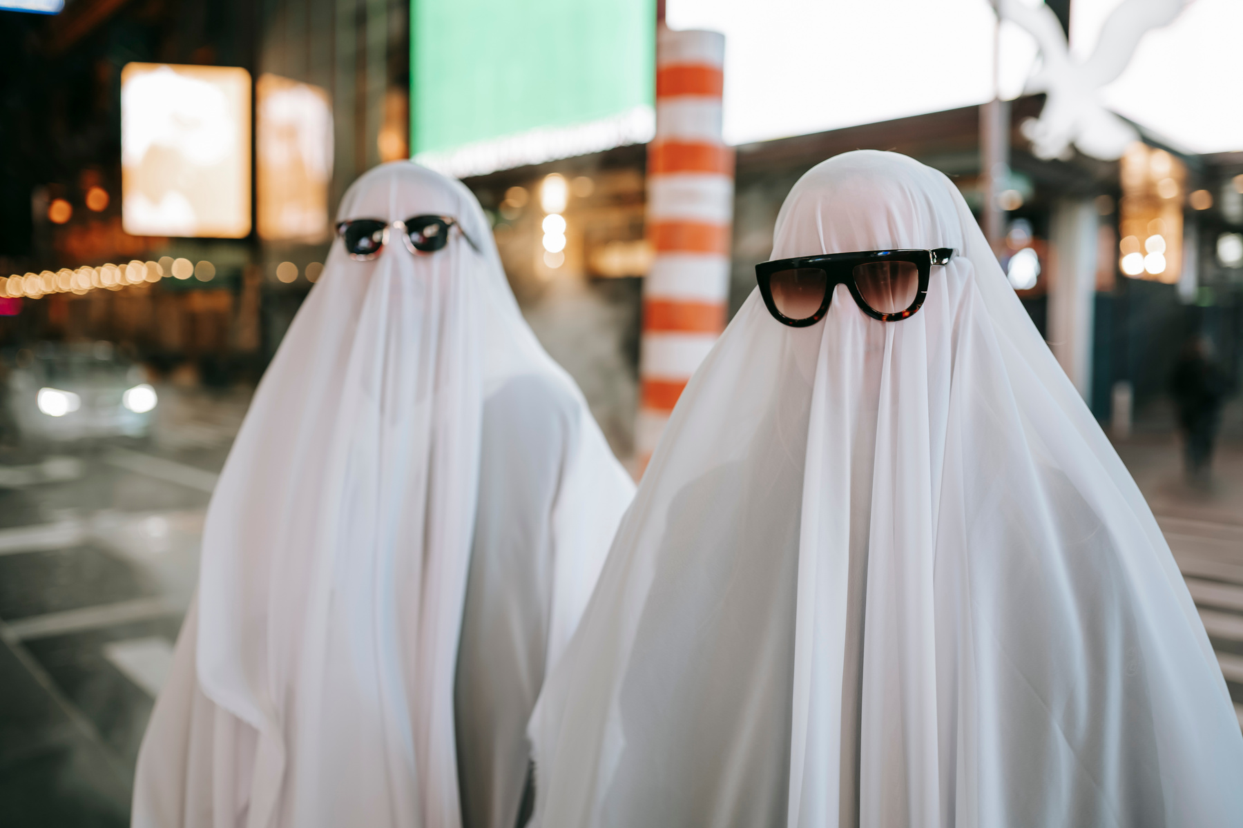 Unrecognizable couple in ghost costumes on night street